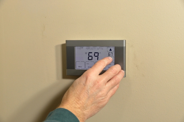 homeowner adjusting smart programmable thermostat
