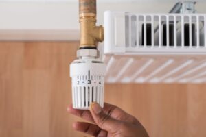 homeowner adjusting oil heating radiator thermostat