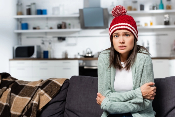 woman in full winter clothes feeling cold indoors due to furnace failure