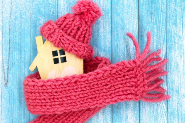 3D wooden miniature model of a house with a scarf and beanie depicting heating oil efficiency