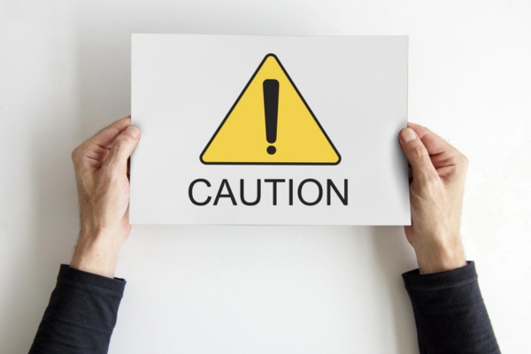 hands holding sign that says caution